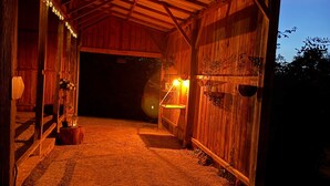 Un granero rústico con interior de madera, un gato en el suelo y ambiente luminoso.