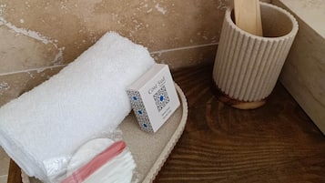 A bathroom with a wooden bath mat, a white towel, a toothbrush, and a wooden brush in a cup.