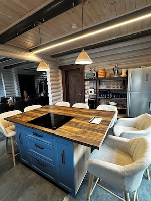 A modern kitchen with a central island, blue cabinetry, and a built-in induction cooktop.
