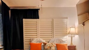 A bedroom with a bed, ottoman, nightstand, lamp, and a TV mounted on the wall. - Private Secure BBQ Man Cave near Beach & Casinos (Hollywood)