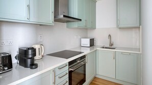 Uma cozinha moderna com armários verde-claros, uma cafeteira Bosch, micro-ondas e pia.
