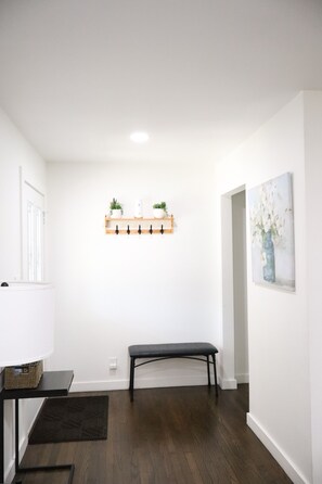 A room with a bench, a wall-mounted shelf with plants, a painting, and a door. - Spacious cozy  5-bedroom house in Dallas (Dallas)