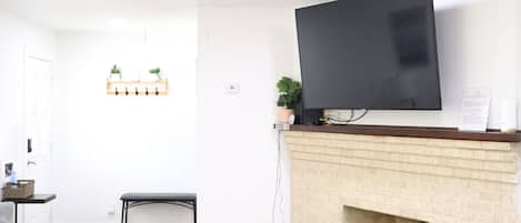 A modern living room with a fireplace, a flat-screen TV mounted above it, a ceiling fan, and a seating area with a sofa and a coffee table.