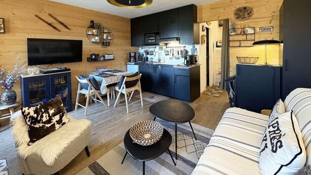Ein modernes Wohnzimmer mit einer Couch, einem Esstisch und einer Küchenzeile.
