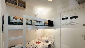 Ein kleines, kompaktes Zimmer mit Etagenbett, Kleiderschrank und Kleiderhaken.
