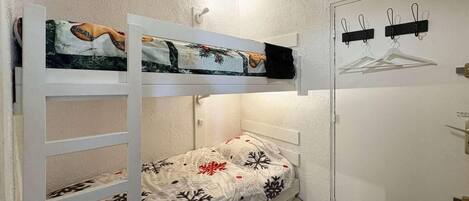 Una stanza piccola e funzionale con un letto a castello, un armadio e un attaccapanni.