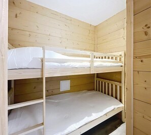 Ein Stockbett mit zwei Schlafstellen, Holzwänden und einer weißen Decke.