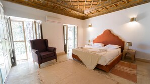 Ein Schlafzimmer mit einem Bett, einem Sessel, einem Nachttisch und einer dekorativen Decke.
