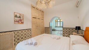 Une chambre d’hôtel comprenant un lit, une armoire, une table de chevet, une lampe et un élément décoratif mural.