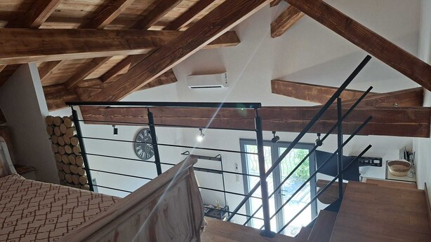Una escalera de madera con barandilla de metal, un reloj y vistas al exterior.