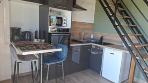 Una cocina compacta con microondas, cafetera y un refrigerador pequeño.