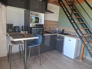 Uma cozinha compacta com micro-ondas, cafeteira e um pequeno frigorífico.