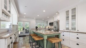 A spacious kitchen with a central island, white cabinetry, and a stone tile floor. - Luxury East Vail Estate w/ Mtn Views & Hot Tub (Vail)