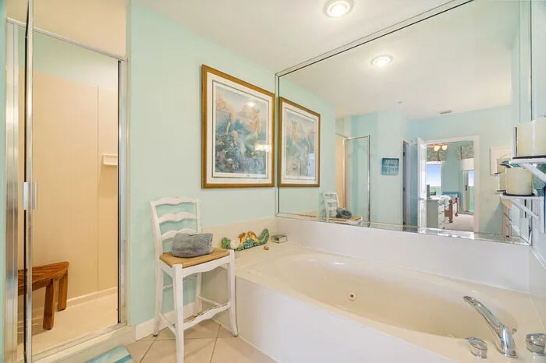 Een badkamer met een badkuip, douche, wastafel en een grote spiegel.