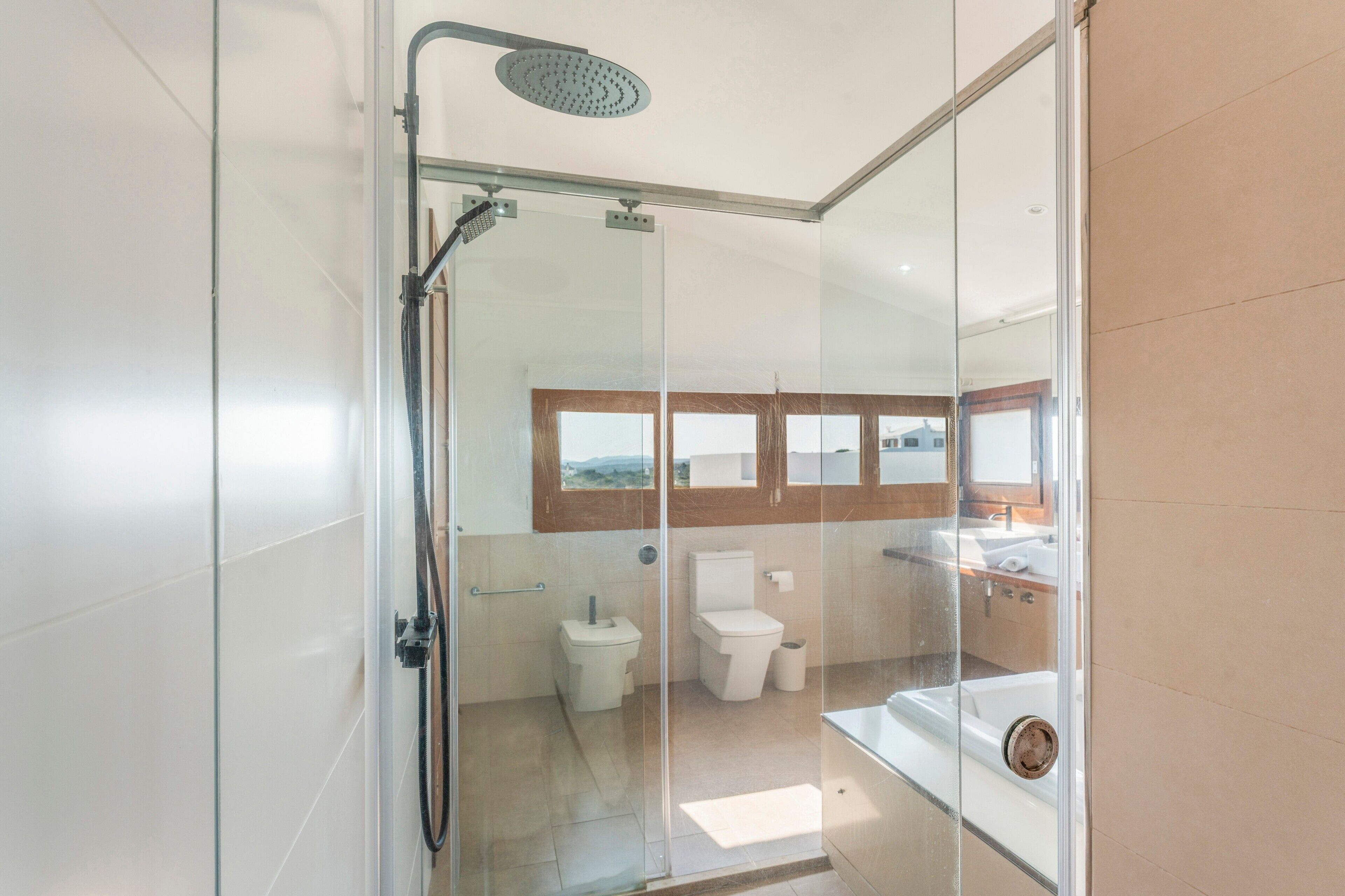 Un baño moderno con cabina de ducha de vidrio, inodoro y lavamanos.