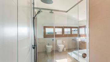 Un baño moderno con cabina de ducha de vidrio, inodoro y lavamanos.