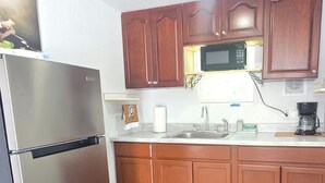 A kitchen with wooden cabinets, a stainless steel refrigerator, a microwave, and a coffee maker. - #33 Private in law suite near USF (Tampa)