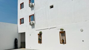 Een gebouw met een zwembad, airconditioners en kleine ramen met planten.
