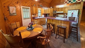 A wooden interior with a dining table, chairs, a kitchen area, and a ceiling fan. - Nature Oasis | Hot Tub | Fishing Pond | Fire Pit (Mentone)