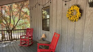 A porch with two rocking chairs and a table, a window, and a yellow wreath on the wall. - Nature Oasis | Hot Tub | Fishing Pond | Fire Pit (Mentone)