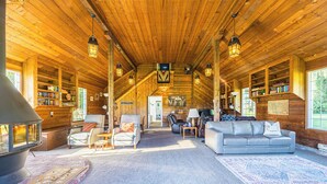 L’intérieur d’une cabane en rondins, avec une cheminée, un coin salon, des étagères et un téléviseur.