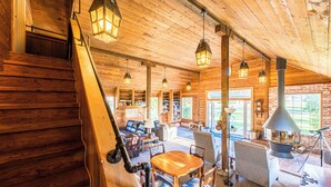 Un intérieur en bois agrémenté d’une cheminée, d’un coin salon et de lanternes suspendues.