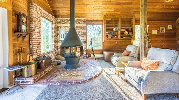 L’intérieur d’un chalet accueillant, avec une cheminée, des murs en bois, un canapé et une bibliothèque.