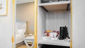 A hotel room with a bed, a small table, a coffee machine, and a tray with snacks and a mug. - Hotel Whiskey in Long Beach (Long Beach)