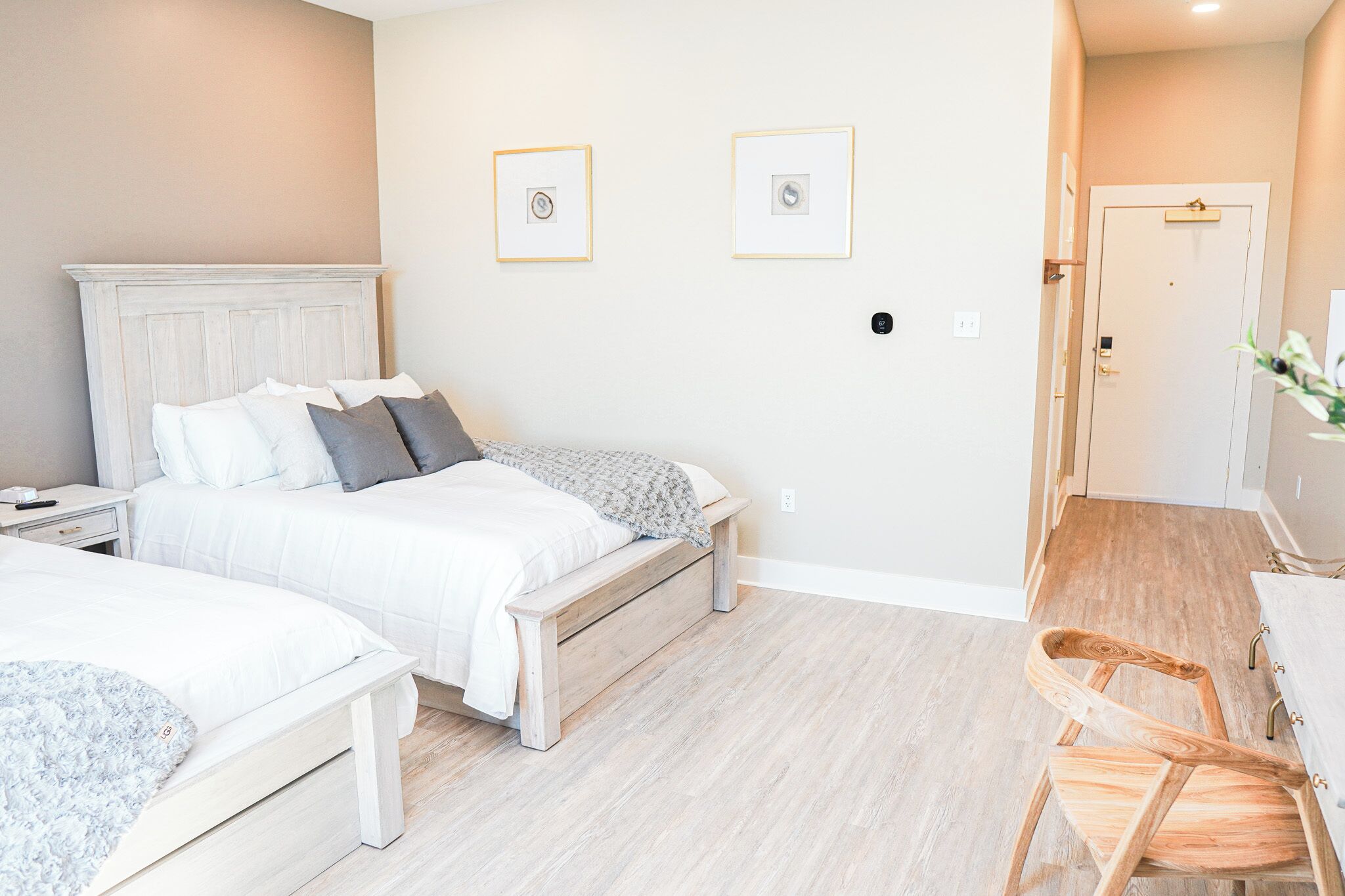 Un dormitorio con dos camas, una silla de madera y una mesita.