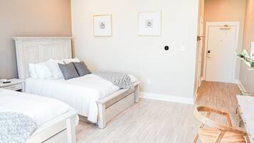 Un dormitorio con dos camas, una silla de madera y una mesita.