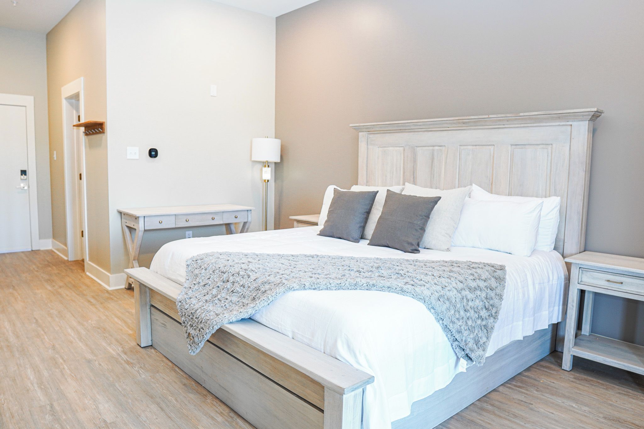 A bedroom with a bed, bedside tables, a lamp, and a door.
