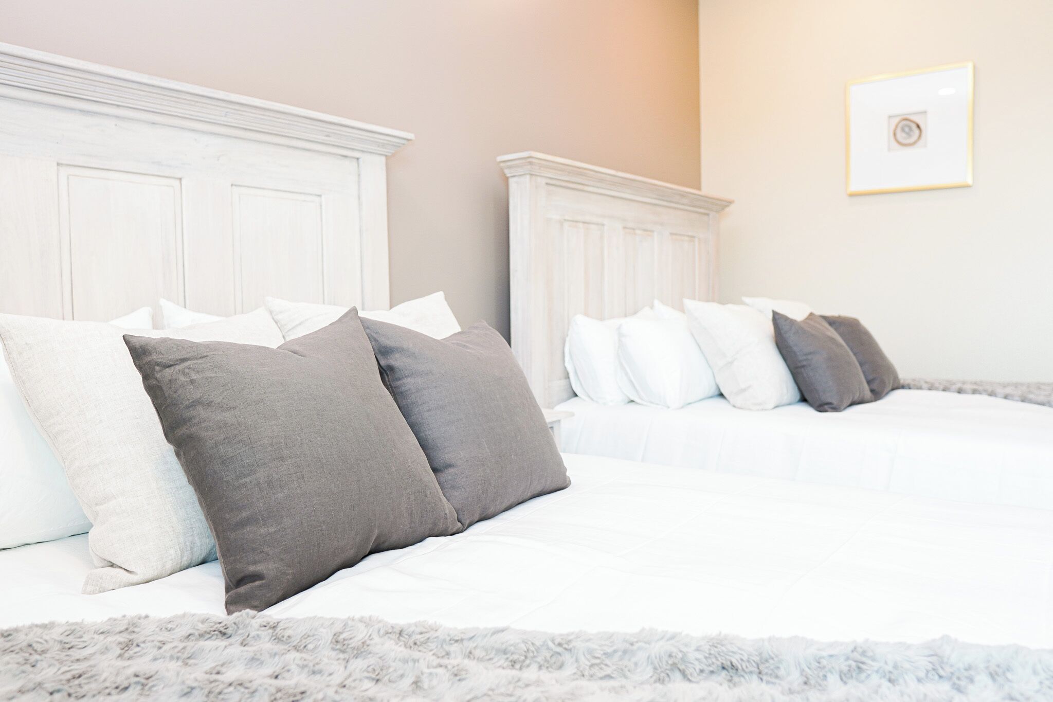 A bedroom with two beds, white headboards, and a fluffy rug.