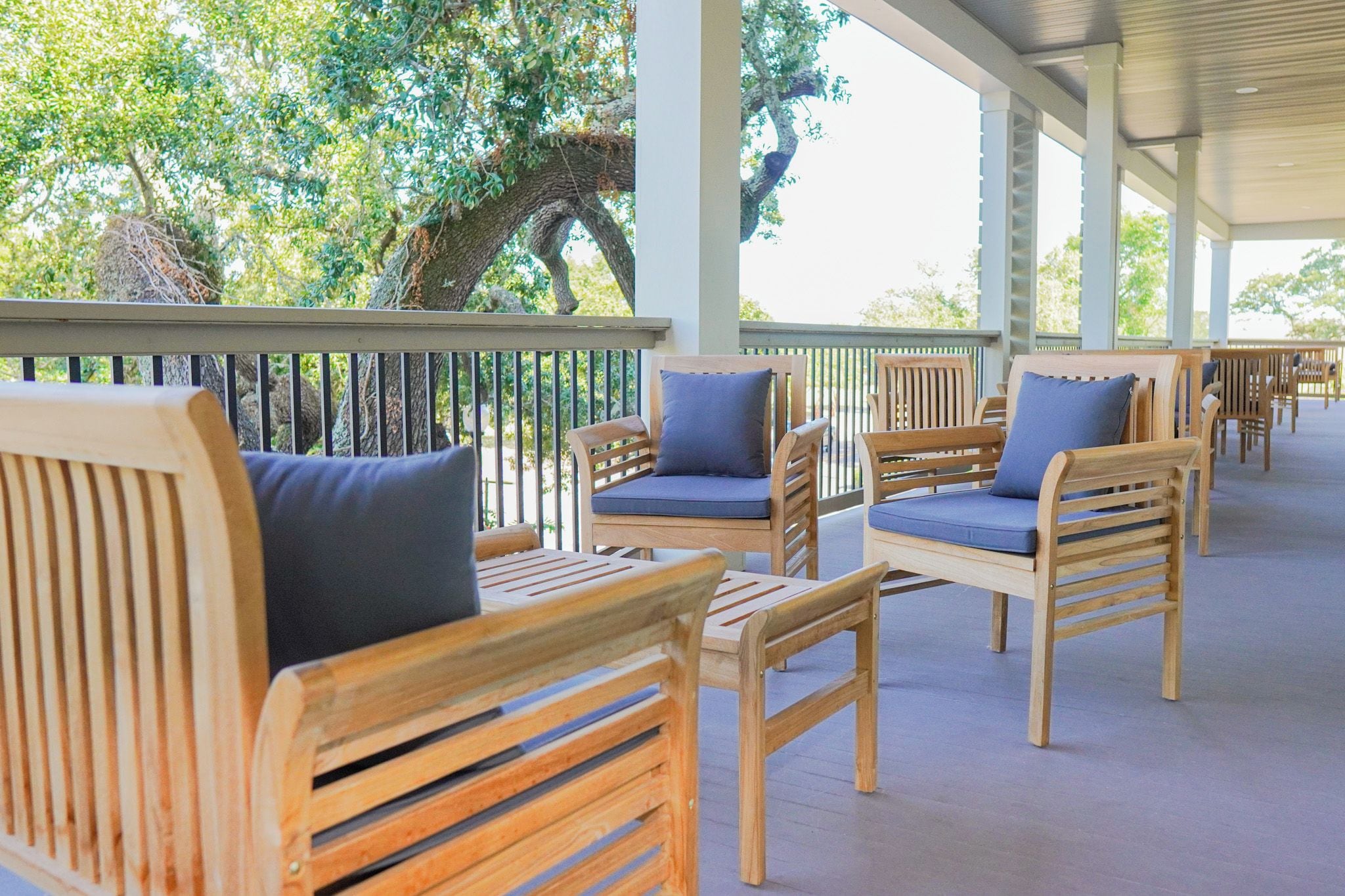 Un espacio de estar al aire libre con techo, muebles de madera y vistas a árboles.