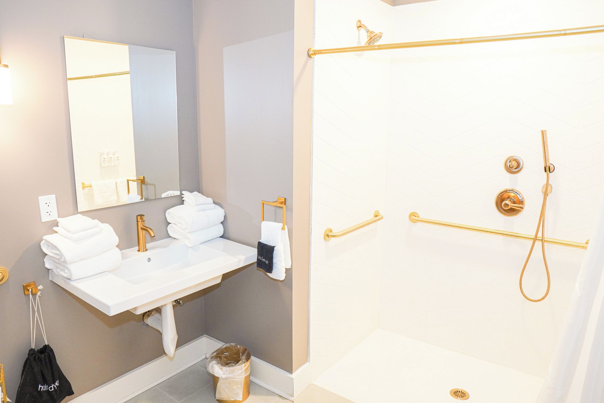 A bathroom with a white sink, gold fixtures, a mirror, and a shower with gold fixtures.