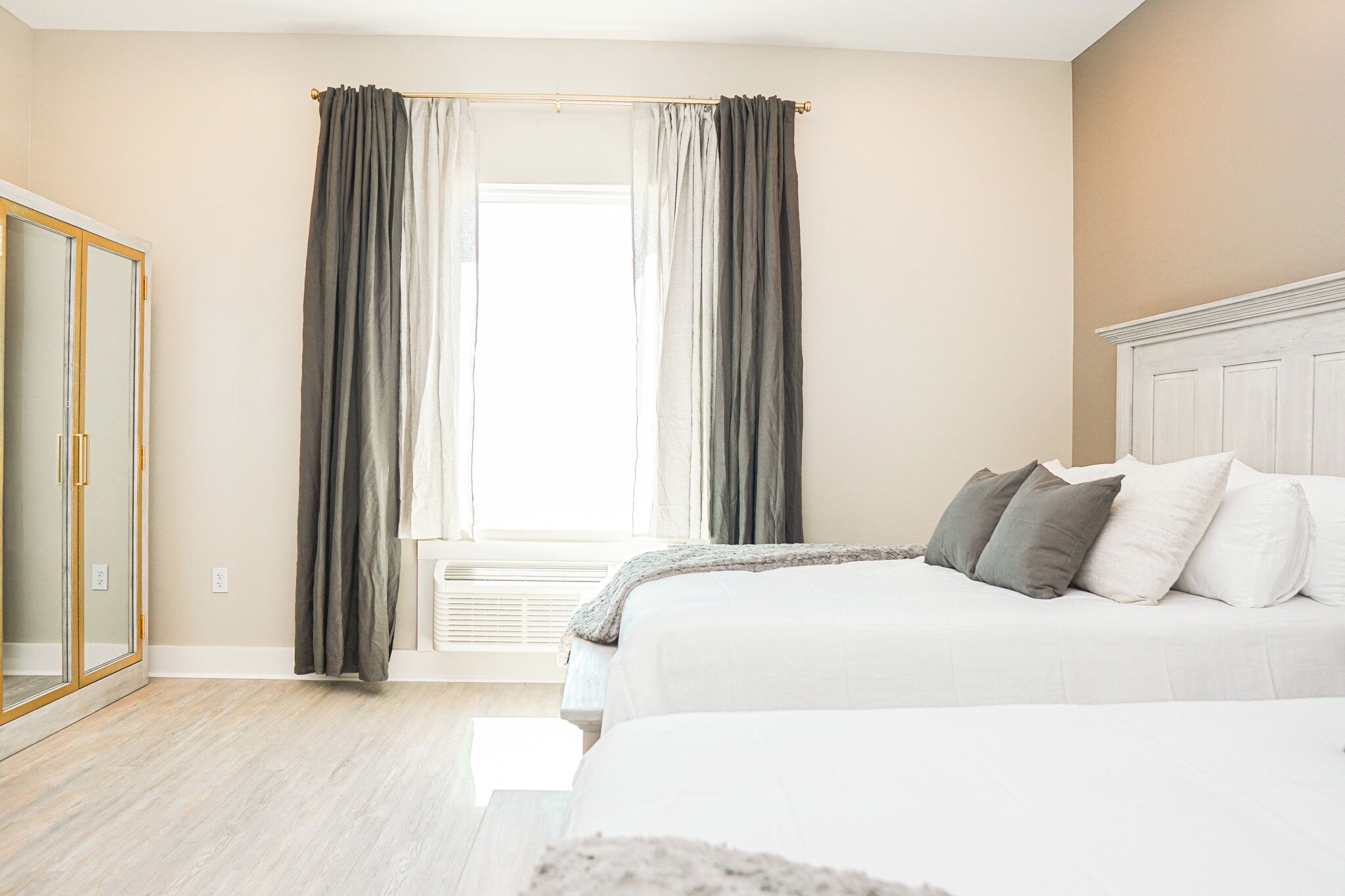 A bedroom with a bed, a wardrobe, and a window with curtains.
