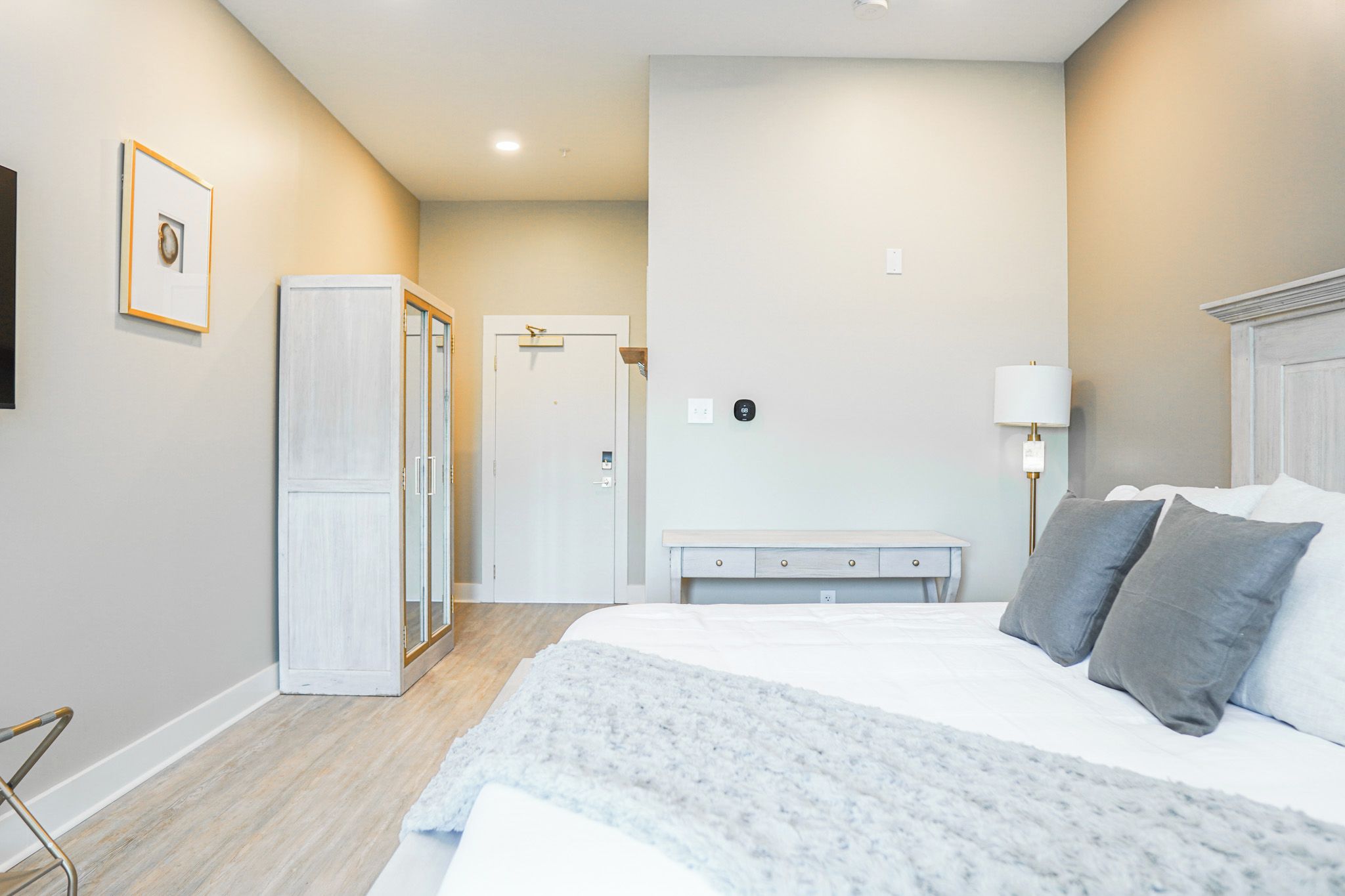 A bedroom with a bed, bedside table, lamp, wardrobe, and a door.