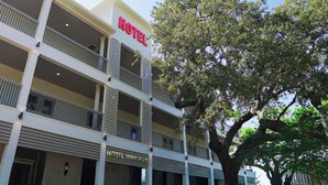 A multi-story hotel with balconies and a large tree in front. - Hotel Whiskey in Long Beach (Long Beach)