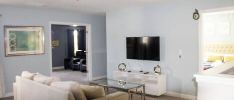 Una sala de estar con sofá, mesa de centro, televisor y escalera.