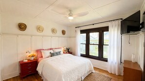 Une chambre à coucher avec un lit, une table de chevet, une lampe et des chapeaux accrochés au mur.