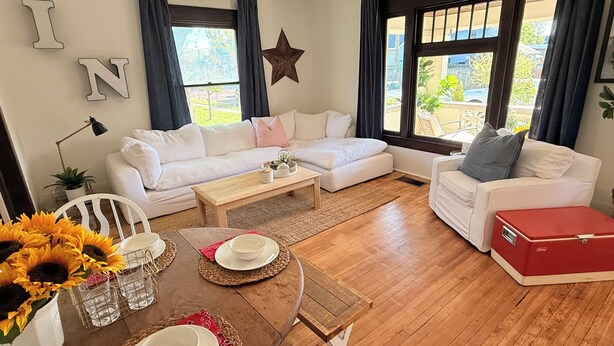 Un salon avec un canapé blanc, une table basse en bois et une boîte de rangement rouge.