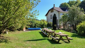 A backyard with a swimming pool, picnic tables, and a house. - In the heart of nature - Gîtes 15 people (Windstein)