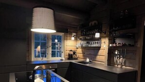 Una cocina moderna con una isla central, iluminación colgante y un ventanal con vistas.