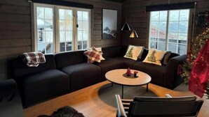 Un salón acogedor con un sofá de color oscuro, una mesa de centro redonda y un árbol de Navidad.