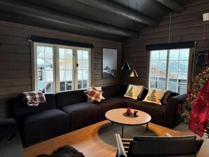 A cozy living room with a dark-colored sofa, a round coffee table, and a Christmas tree. - Kongelberget 105 - Exclusive mountain cabin with jacuzzi & Sauna at Bjorli (Innlandet)