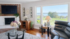 Un salón con chimenea, un sofá, una mesa de centro y vistas a un lago.