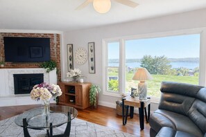 Un salón con chimenea, un sofá, una mesa de centro y vistas a un lago.