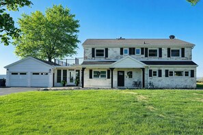 Une maison à deux étages avec un garage, une véranda et une grande pelouse.
