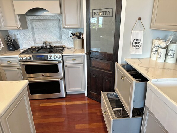 A kitchen with white cabinetry, a stainless steel stove, and a dishwasher.