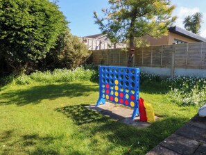 A blue pegboard game set in a grassy yard with a wooden fence and a tree in the background. - 20 Gwelfor Estate (Cemaes Bay)