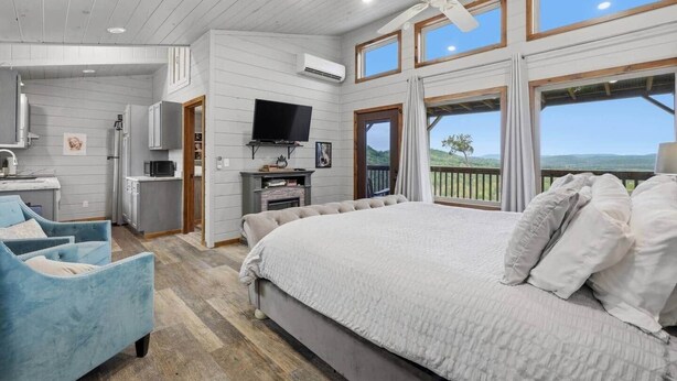 Een slaapkamer met een groot bed, een televisie, een openhaard en een balkon met uitzicht.
